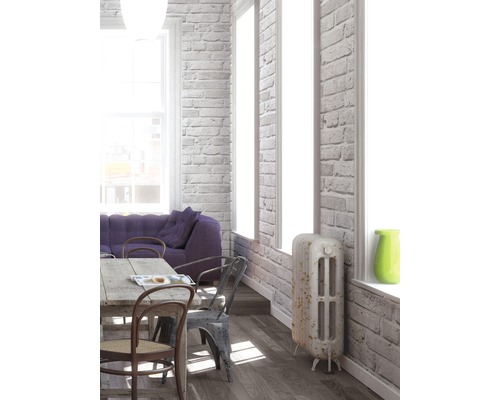 Espace de vie lumineux avec table à manger, chaises, canapé et radiateur devant un mur de briques