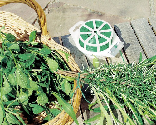 Pflanzenbinder und Korb mit frischen Kräutern auf Holztisch