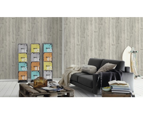 Wohnzimmer mit grauer Holzoptik Tapete, schwarzem Sofa und bunten Metallschränken als Dekoration.