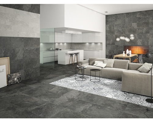 Wohnraum mit Boden- und Wandfliesen in Steinoptik, Sofa und offener Küche