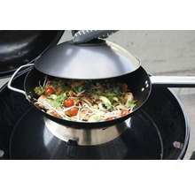 Wok avec couvercle sur barbecue avec plat de légumes