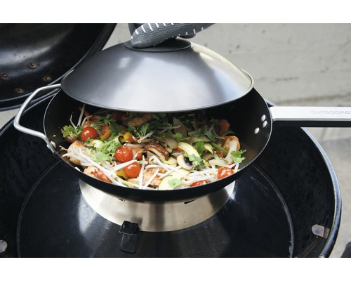 Wok avec couvercle sur barbecue avec plat de légumes