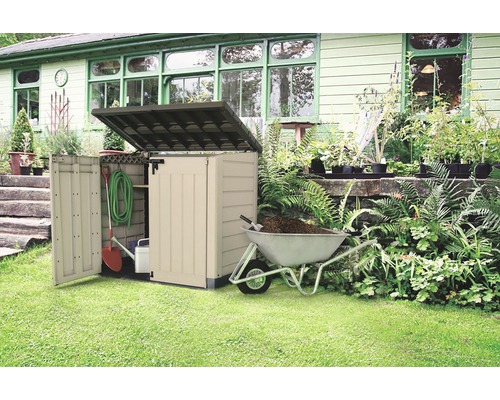 Gartenszene mit einer Gartengerätebox, einer Schubkarre und Gartengeräten.