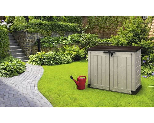 Gartenszene mit einem Gerätehaus, einer Gießkanne und einem gepflegten Garten