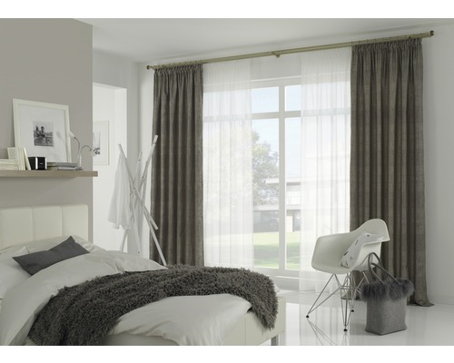 Chambre lumineuse avec lit, chaise et rideaux sur une tringle à rideaux devant la fenêtre.