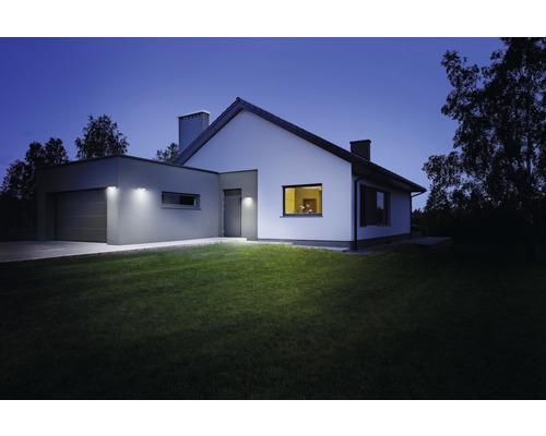 Maison individuelle avec éclairage extérieur et pelouse la nuit