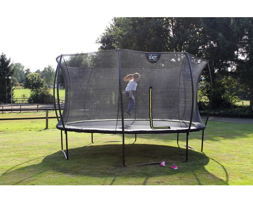 Trampoline avec filet de sécurité dans le jardin, un enfant saute