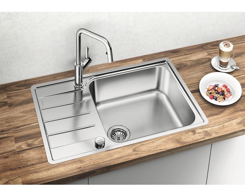 Évier en acier inoxydable avec égouttoir et robinet sur un plan de travail en bois