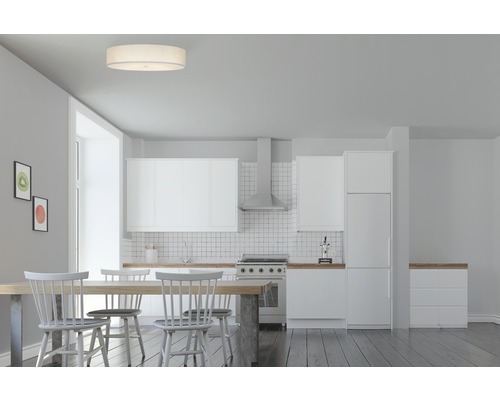 Heller Speisesaal mit Esstisch, Stühlen, Deckenleuchte und Küchenzeile