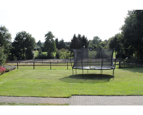 Trampoline de jardin gonflable avec filet de sécurité sur une pelouse.