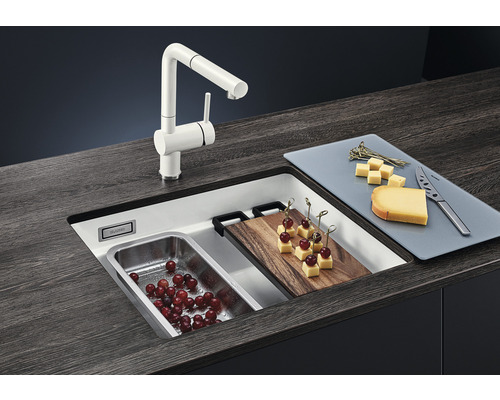 Spüle mit Armatur, Schneidebrett und Lebensmitteln auf einer Küchentheke.