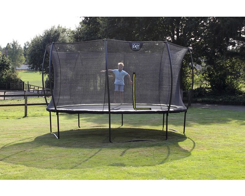 Trampolin mit Sicherheitsnetz im Garten, ein Kind springt.
