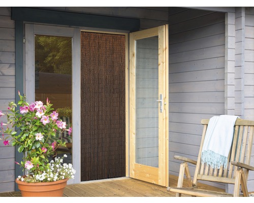 Scène avec porte en bois, rideau anti-insectes, chaise en bois et plante en pot devant une maison en bois