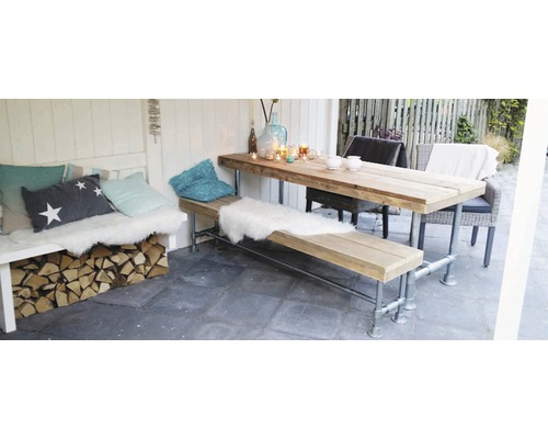 Holztisch und Bank mit Kissen und Dekoration in einem Gartenbereich