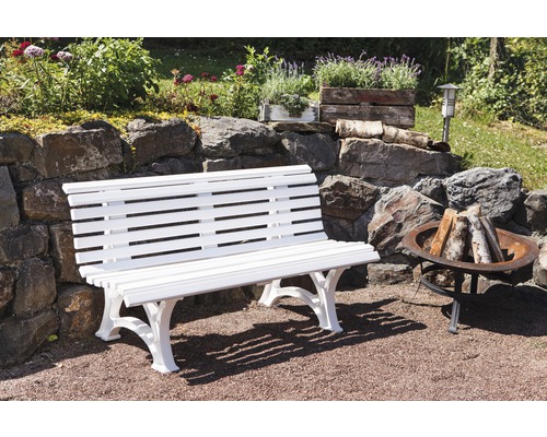 Banc de jardin en bois blanc devant un mur de pierre
