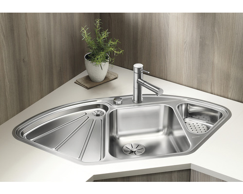 Évier d''angle en acier inoxydable avec égouttoir et robinet sur un plan de travail clair