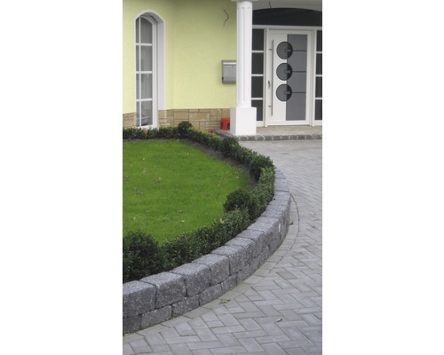 Gartenlandschaft mit Rasenfläche, Steinmauer und gepflastertem Weg