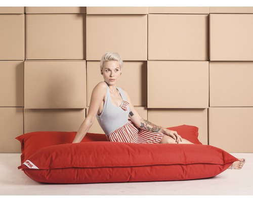 Femme assise sur un pouf rouge devant des cartons de déménagement