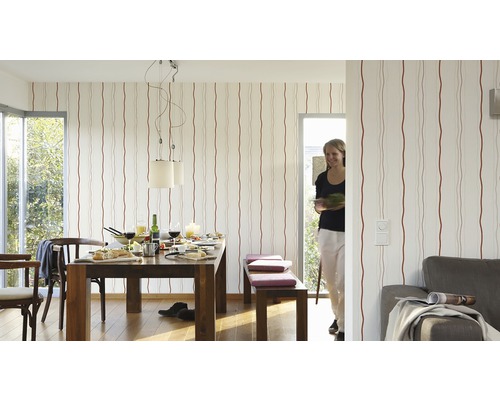 Salle de séjour avec table à manger, chaises, banc et papier peint rayé pour une ambiance lumineuse et conviviale.