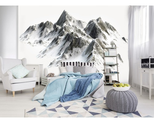 Schlafzimmer mit Bergmotiv-Tapete, Bett, Sessel und Teppich