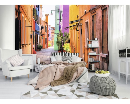 Salon avec papier peint photo d''une ruelle colorée, fauteuil, lit et tapis