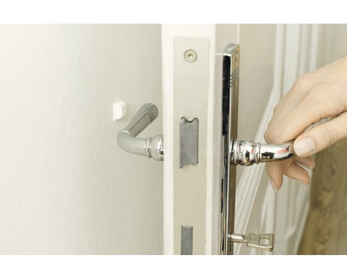 Une main ouvre une porte avec une poignée et une serrure de couleur argent