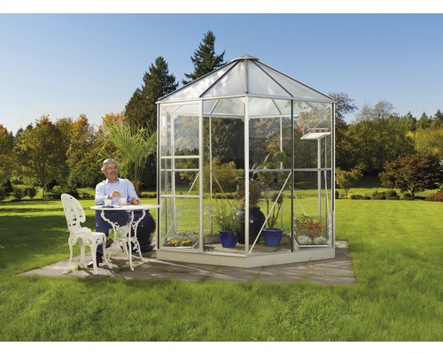 Serre en verre autoportante avec un homme assis à une table