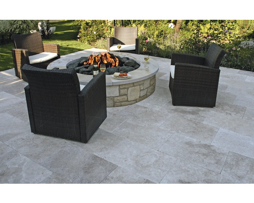 Gartenszene mit Feuerstelle, Steinfliesen und Korbsesseln