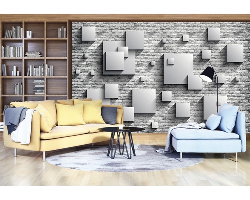 Wohnzimmer mit gelbem Sofa, blauem Sessel, Bücherregal und einer Tapete mit Würfelmuster