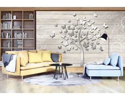 Salon avec bibliothèque, canapé, fauteuil, table basse et papier peint avec motif d''arbre à papillons.