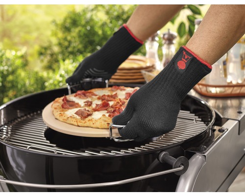 Une pizza est placée sur un barbecue avec des gants de barbecue.