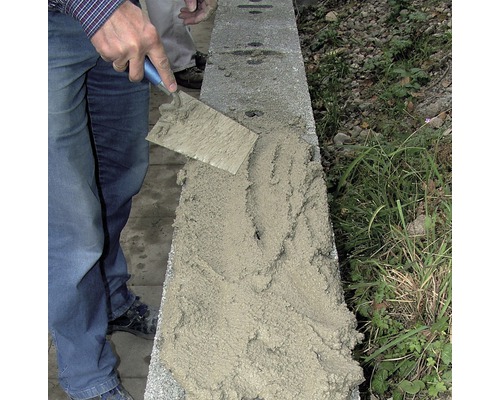 Un artisan applique du mortier sur un mur à l''aide d''une truelle.