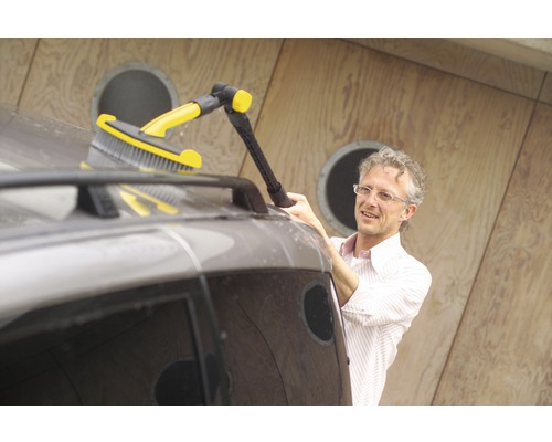 Un homme nettoie une voiture avec une brosse de lavage