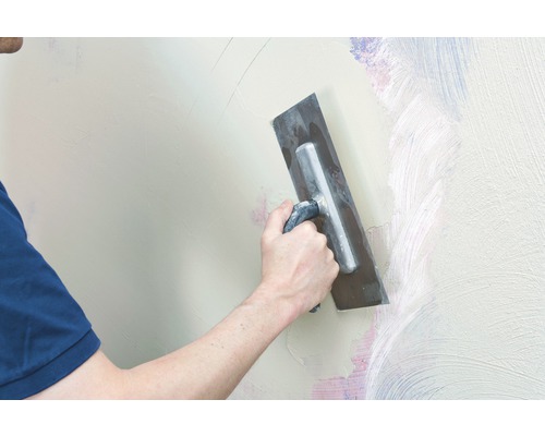 Artisan lissant un mur avec une lisseuse