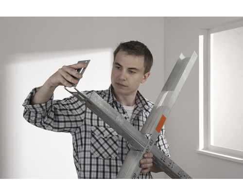 Un homme assemble des profilés de construction sèche avec un angle de fixation