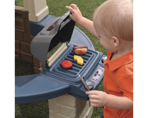 Un enfant joue avec un barbecue jouet et des aliments jouets