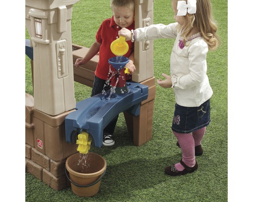 Deux enfants jouent avec une table d''eau à l''extérieur et versent de l''eau dans un seau.