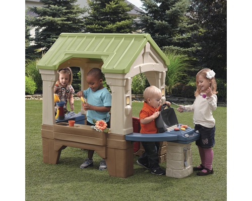 Maisonnette avec barbecue et enfants jouant dans le jardin