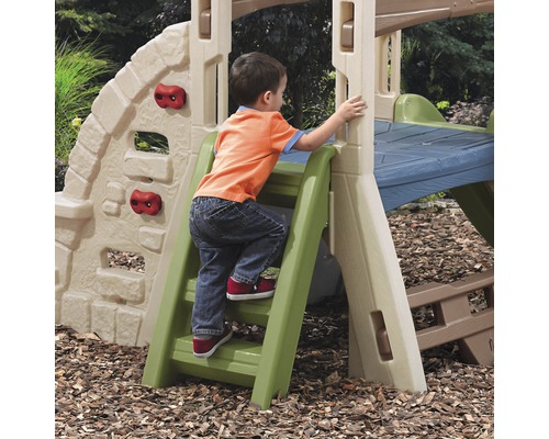 Un enfant grimpe sur une combinaison de jeux d''extérieur avec mur d''escalade et toboggan.