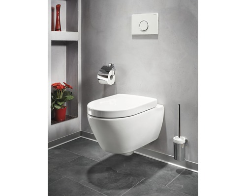 Hänge-WC in einem Badezimmer mit Toilettenpapierhalter, Spülknopf und WC-Bürste