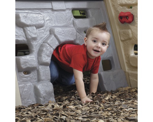Un enfant rampe dans un tunnel de jeu avec mur d''escalade dans le jardin.