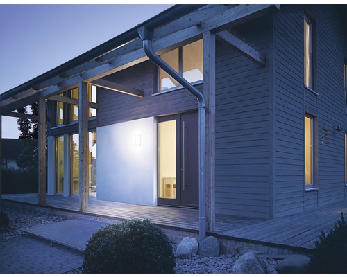 Beleuchtetes Wohnhaus mit Holzfassade und Holzterrasse bei Dämmerung