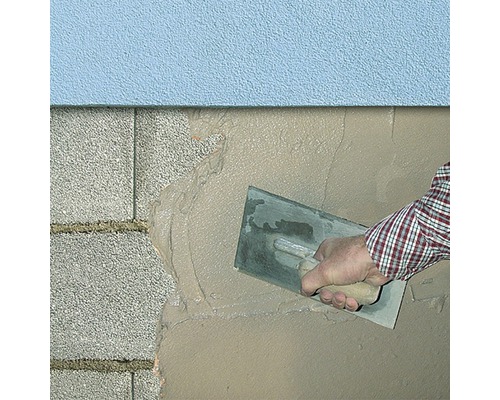 Application de plâtre sur un mur avec une truelle.