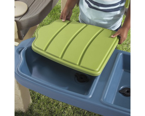 Gros plan sur un enfant posant un couvercle vert sur une cuisine d''eau bleue.