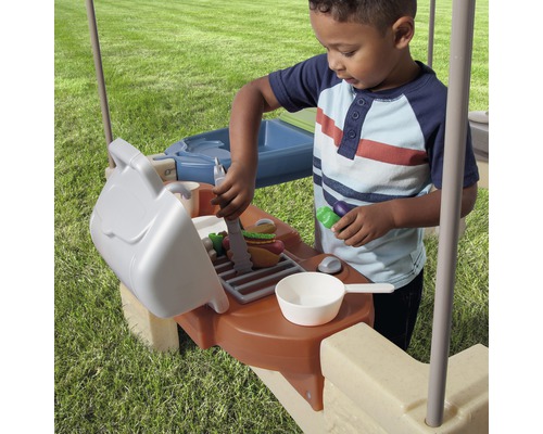 Un enfant joue avec un barbecue jouet à l''extérieur