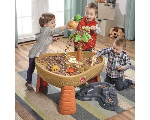 Trois enfants jouent avec une table de sable et d''eau Step2 Dino avec des accessoires et des dinosaures à l''intérieur.