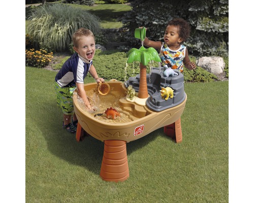 Des enfants jouent avec une table de jeu d''eau dinosaure dans le jardin.