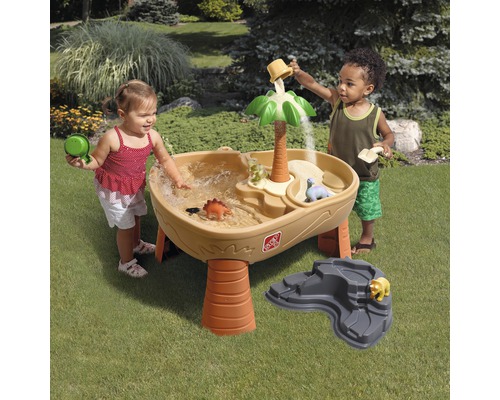 Des enfants jouent avec une table de jeu d''eau sur le thème des dinosaures à l''extérieur.