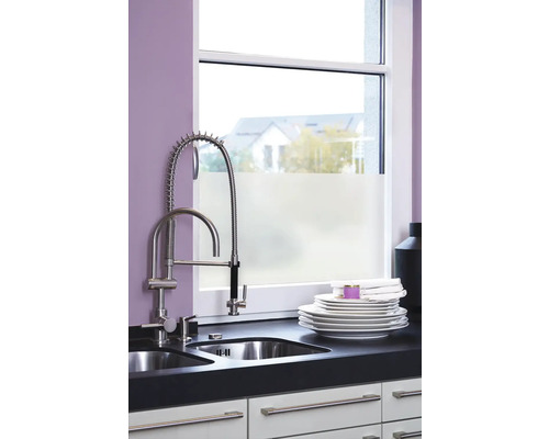 Küchenspüle mit Geschirr und Armatur vor einem Fenster.