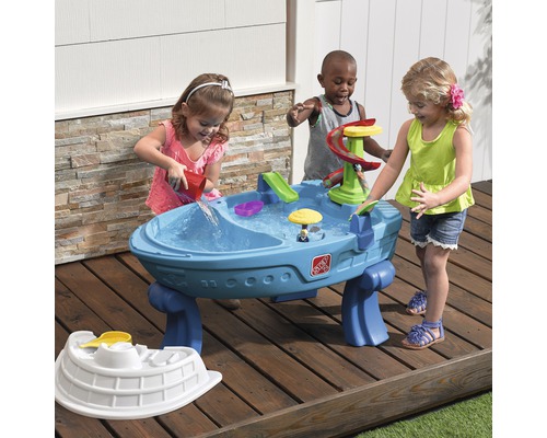 Des enfants jouent avec une table d''eau Step2 bleue à l''extérieur.